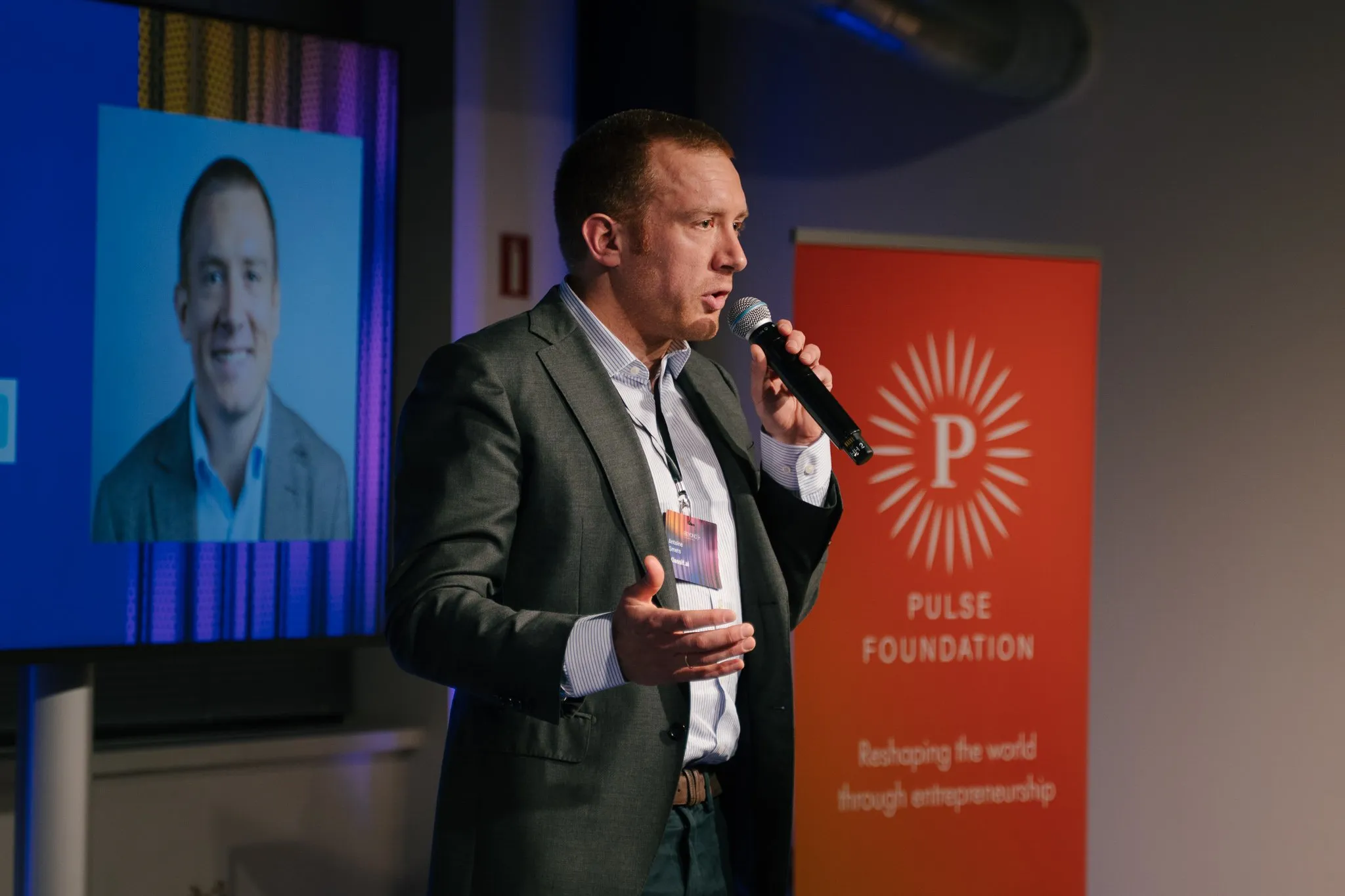 A founder speaking with a microphone at a BEyond evening, in front of the Pulse Foundation banner.