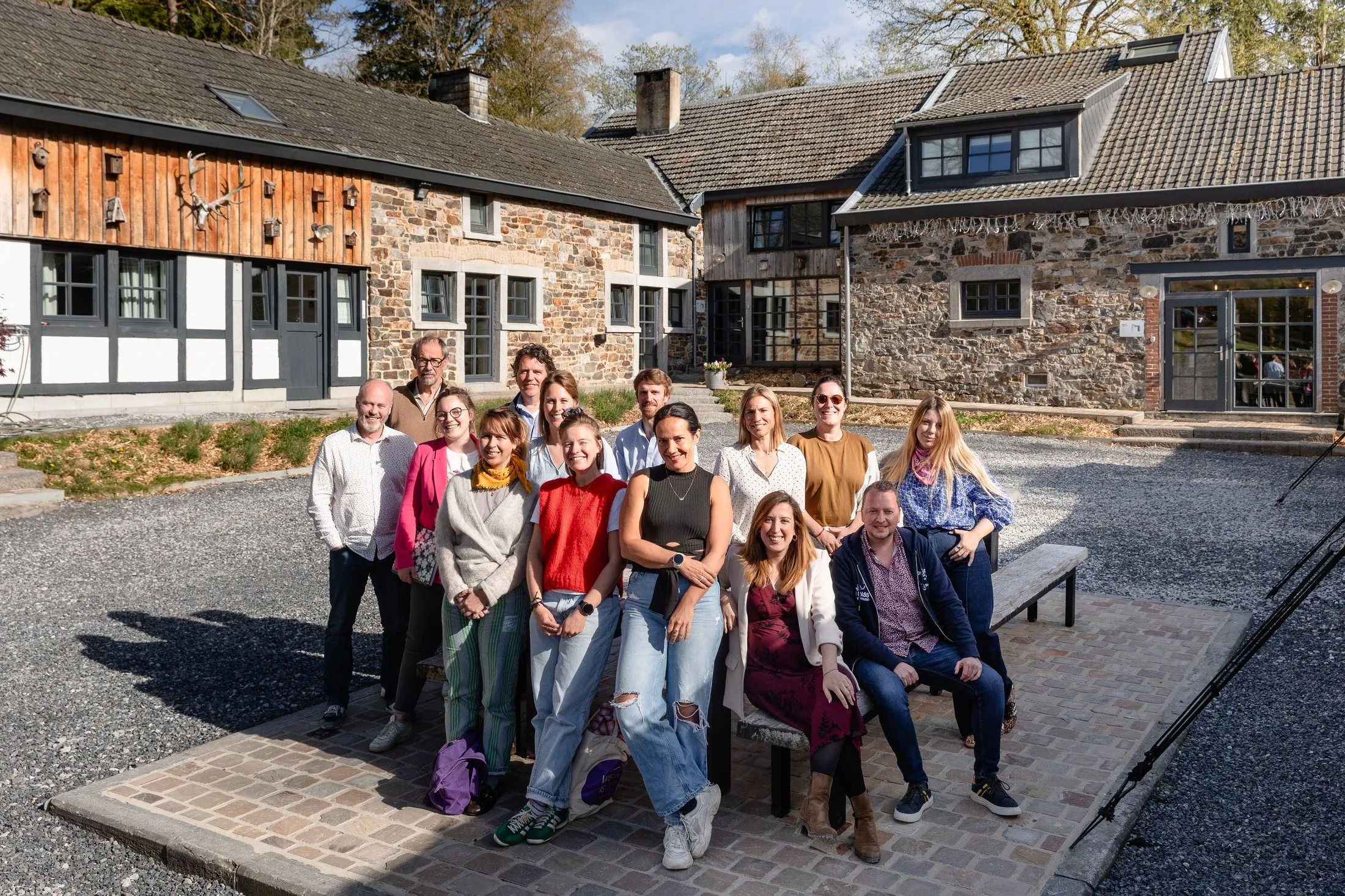 A RISE cohort together in the courtyard of a stone farmhouse in the Ardennes, in spring sunshine.